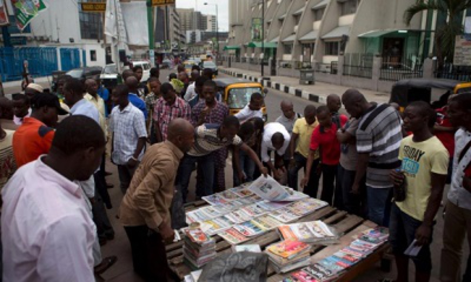 People gathered around a newspaper stand in a Nigerian city